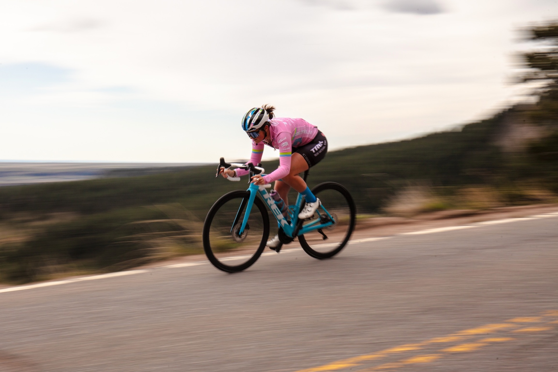 Bayli descending at speed in a pink Trek Bear Pro kit, motion blur background