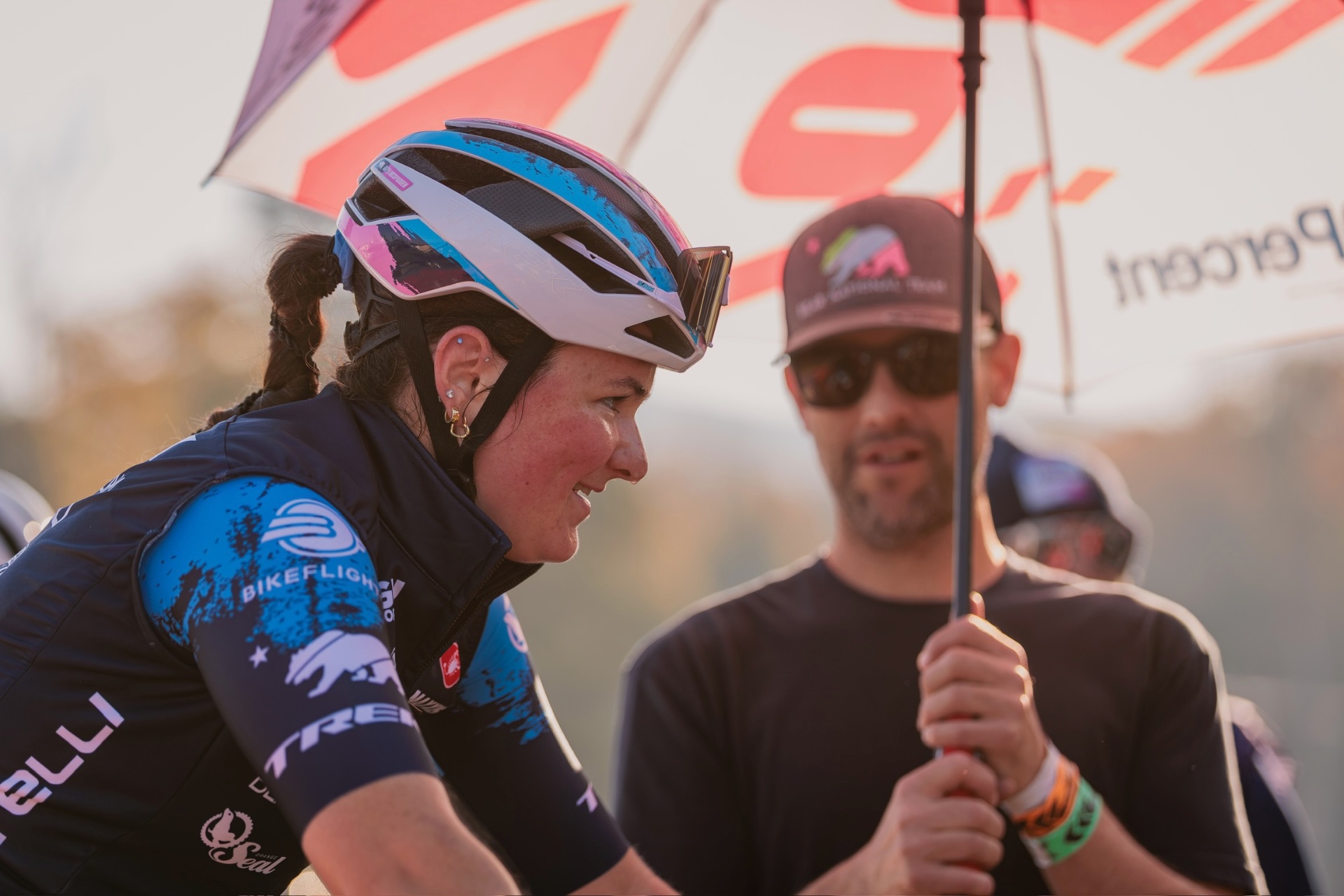 Bayli sharing a laugh with her coach at sunset under a Castelli umbrella