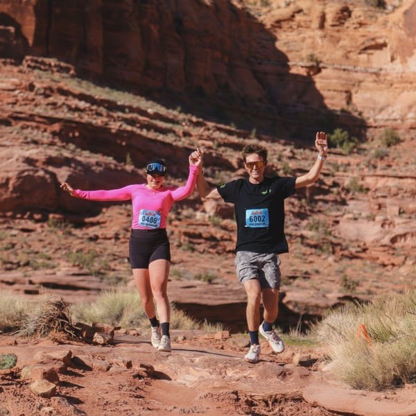 Bayli holding hands with a friend at a Moab trail race in desert red rock