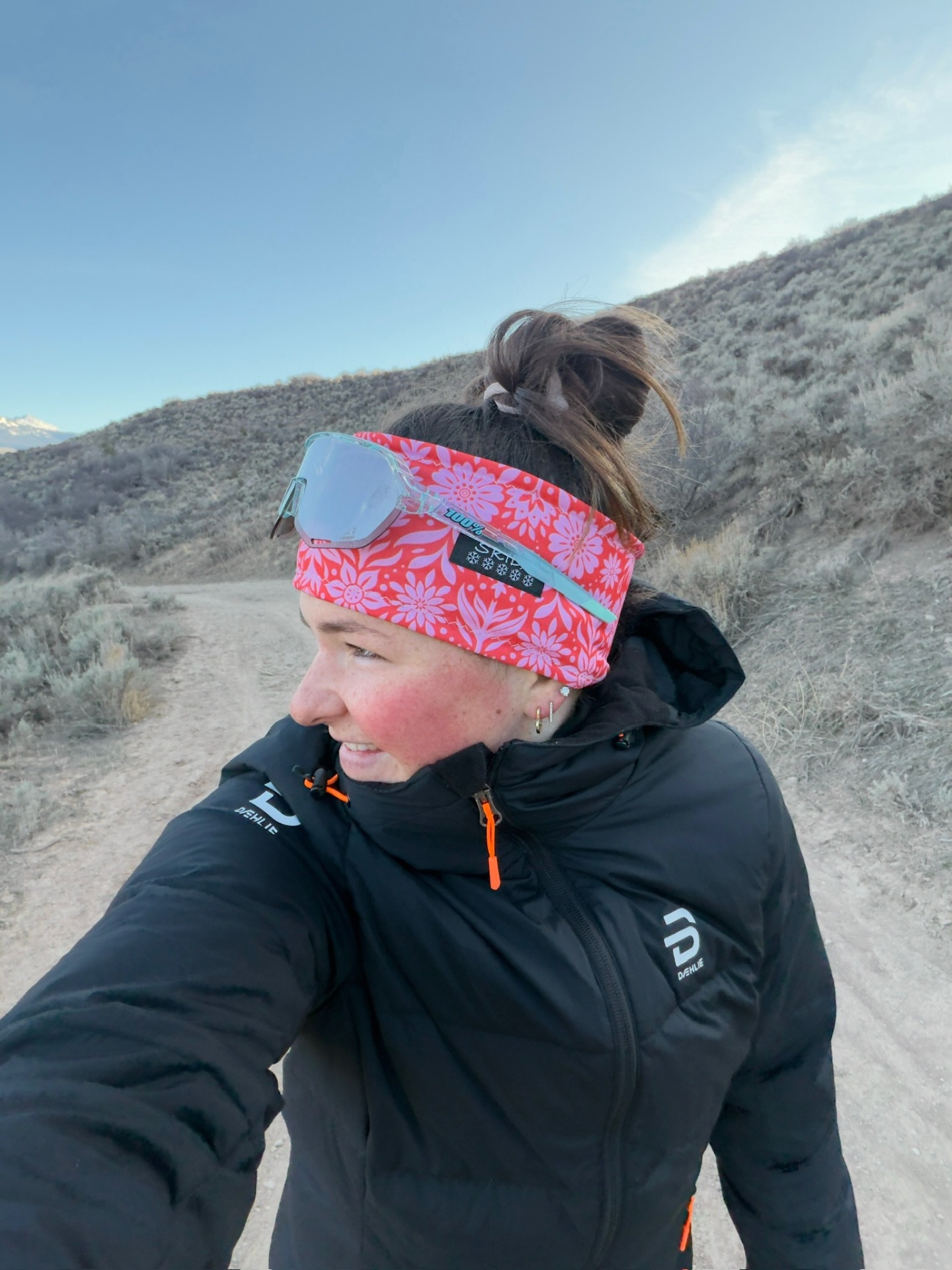 Bayli in a pink floral headband and Bjørn Dæhlie puffer on a sagebrush trail at dawn