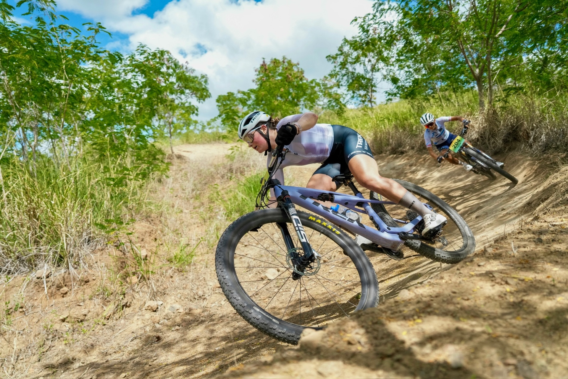 Bayli railing a dusty berm on the Trek Supercaliber in the Dominican Republic
