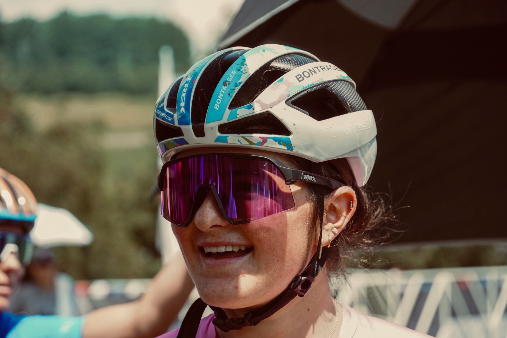 Close-up portrait of Bayli in a Trek Bontrager helmet and pink 100% sunglasses